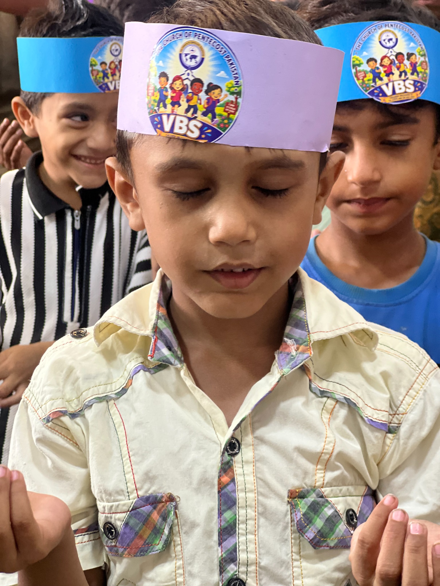 A young participant wears a handmade Vacation Bible School headband.