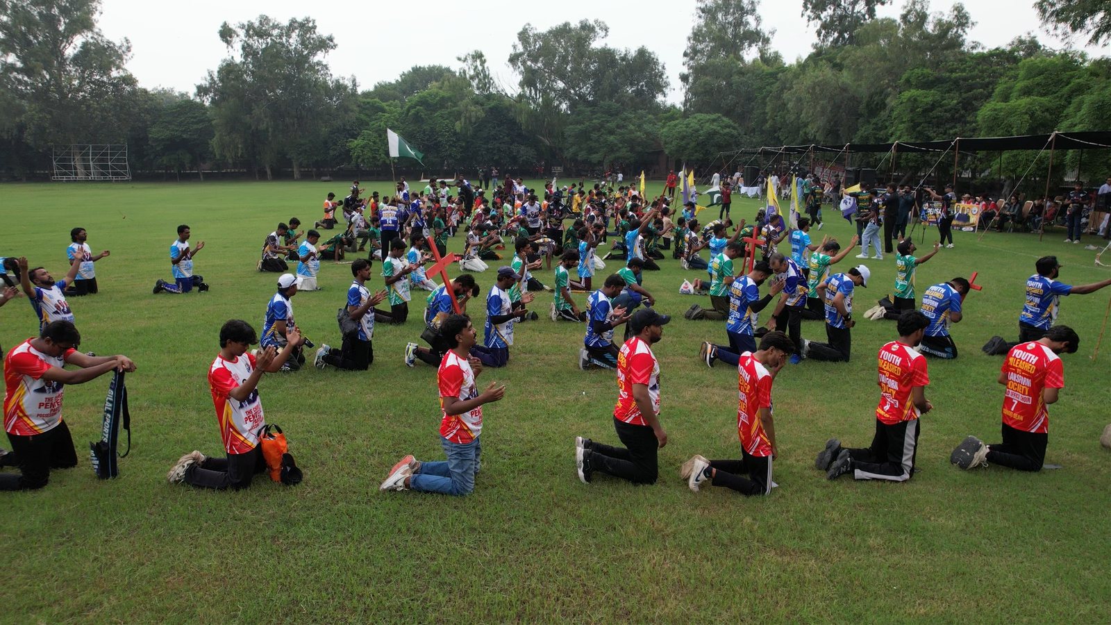 Hundreds of young believers kneel together in prayer.