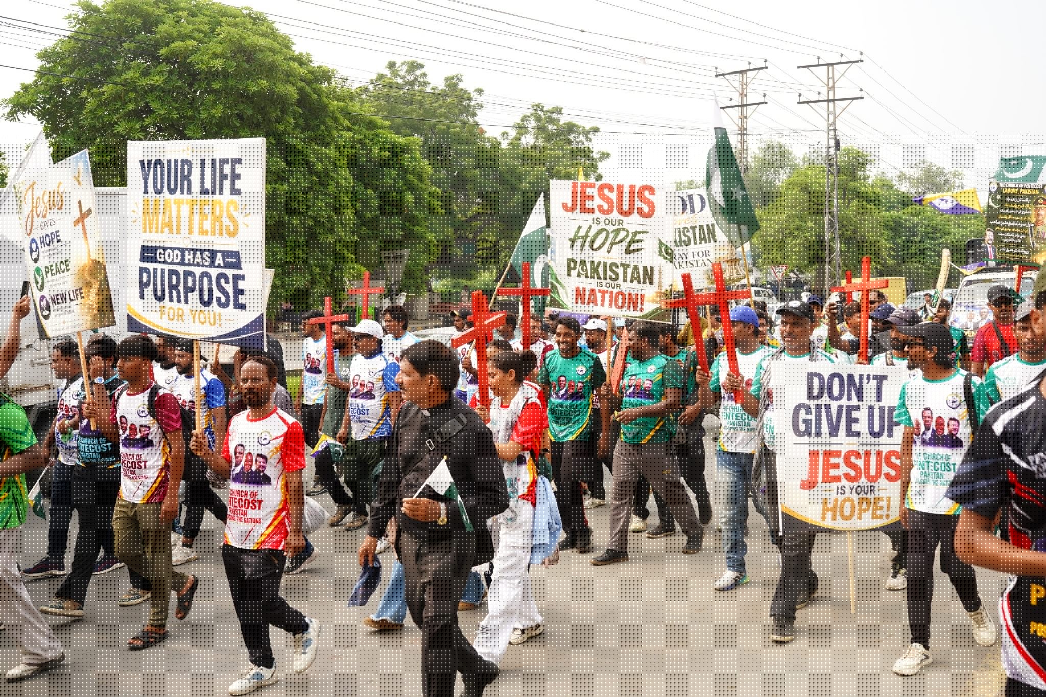 Young believers, pastors and church leaders carry crosses, flags and Gospel banners through Lahore.